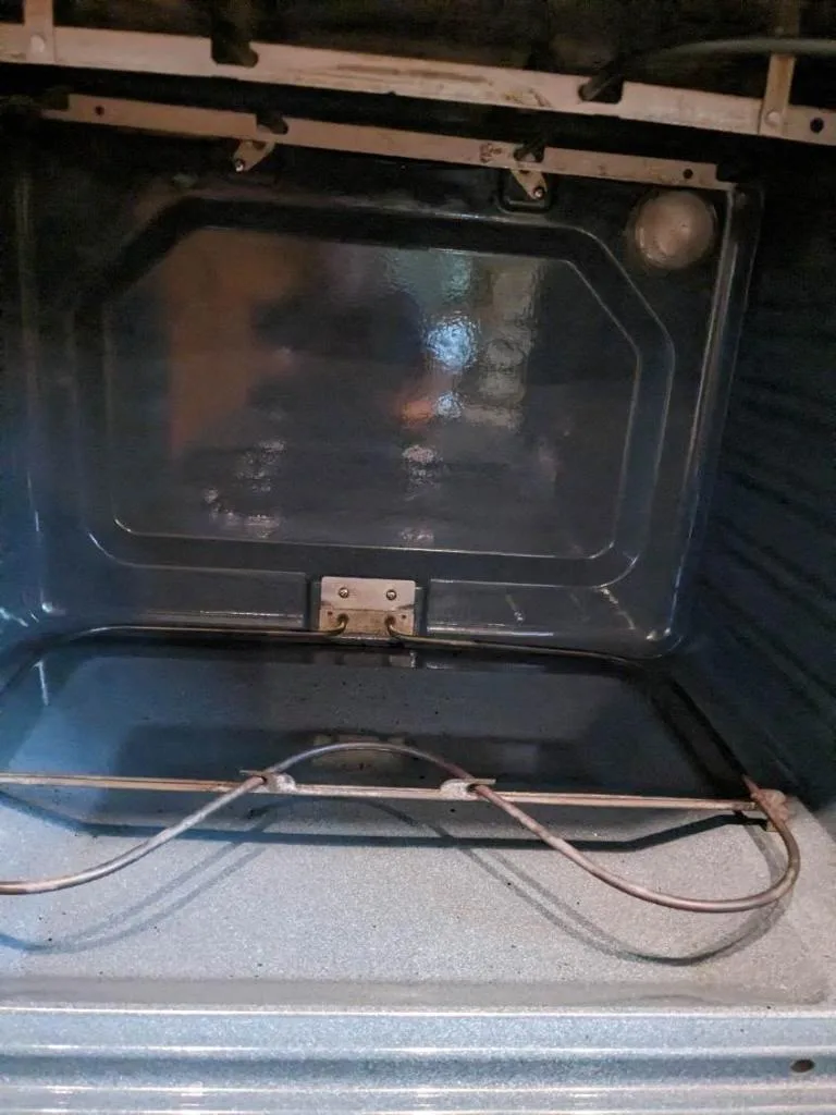 Interior de horno con restos de suciedad y residuos, mostrando el trabajo necesario en limpieza post construcción