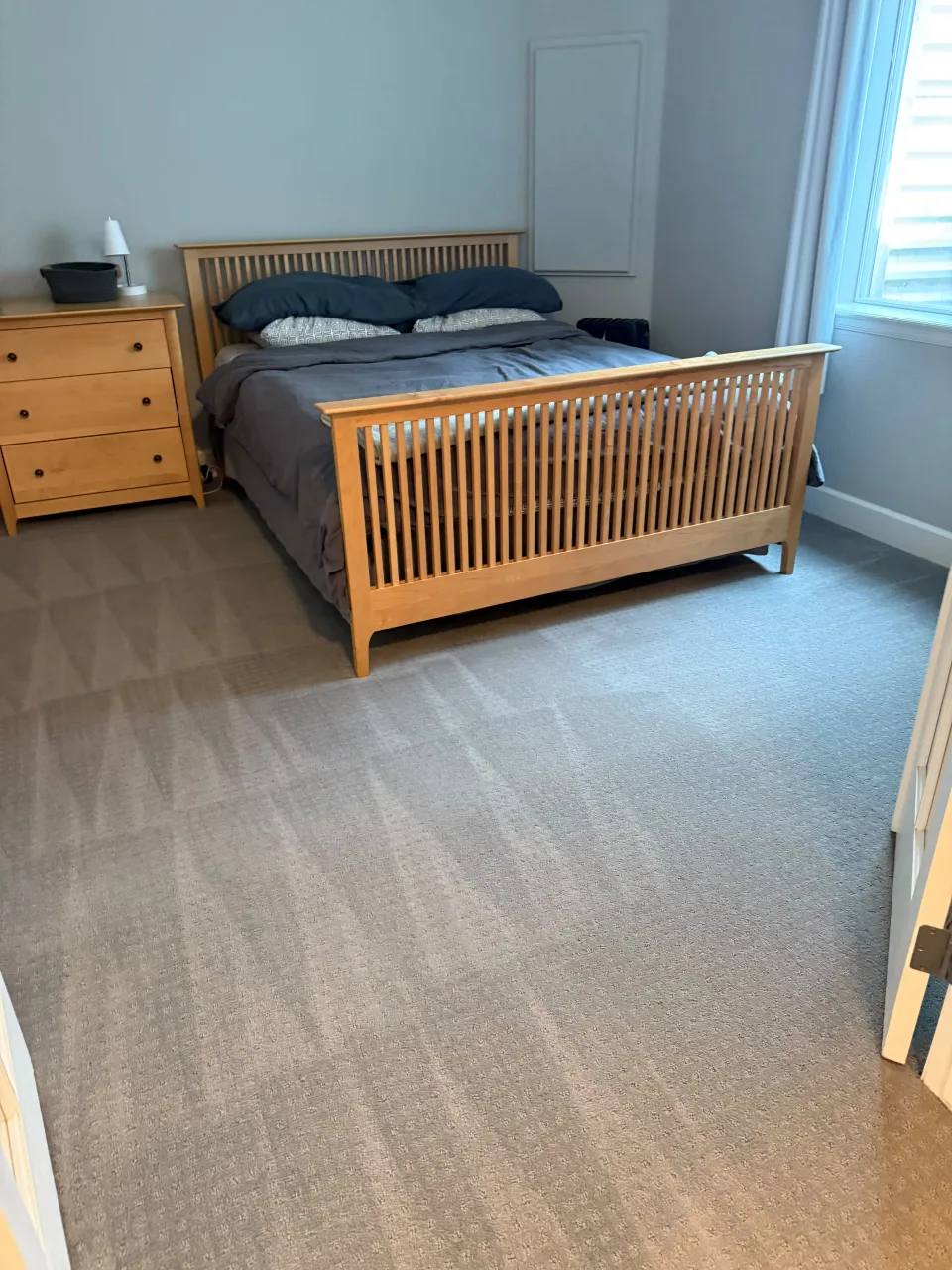 Habitación vacía y ordenada con cama de madera y cómoda, lista para mudanza, con alfombra impecable