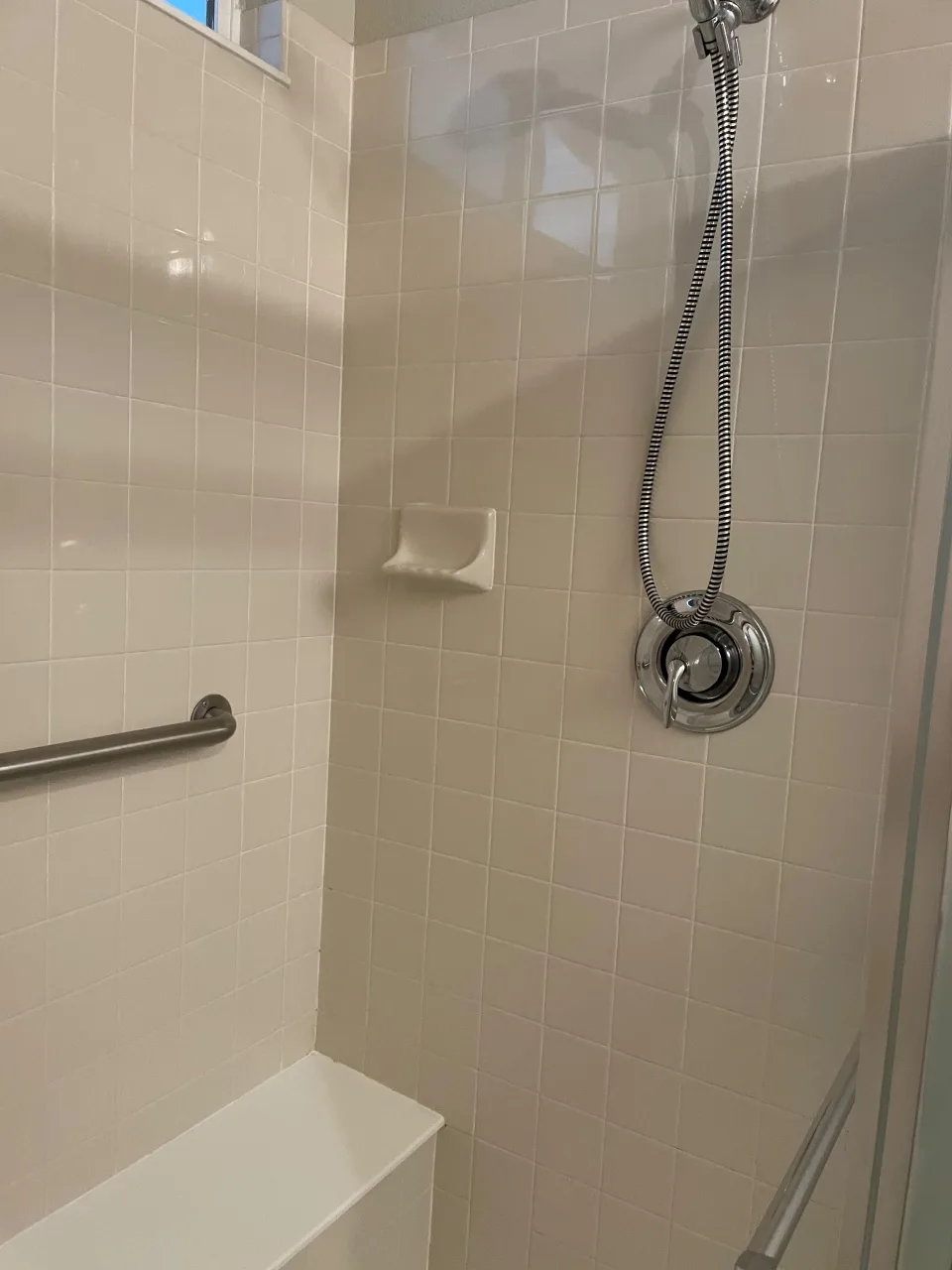 Ducha de azulejos blancos con grifería cromada reluciente tras una limpieza profunda